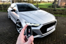 a-person-holding-a-car-key-in-front-of-a-silver-car.jpg a person holding a car key in front of a silver car